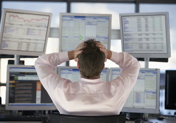 Image of a trader looking stressed out at his computer screen